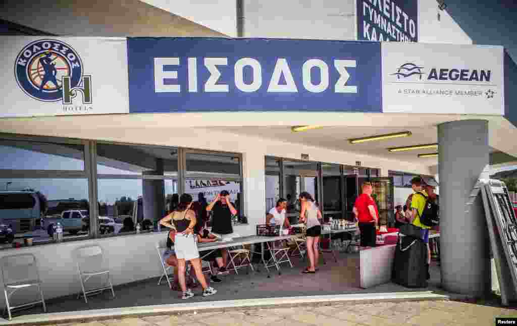 Turisti ispred stadiona nakon što su evakuirani zbog požara. "Ovo je najveća požarna evakuacija ikada u Grčkoj", izjavila je za AFP Konstantia Dimoglidou, glasnogovornica grčke policije. "Morali smo evakuirati područje od 30.000 ljudi."