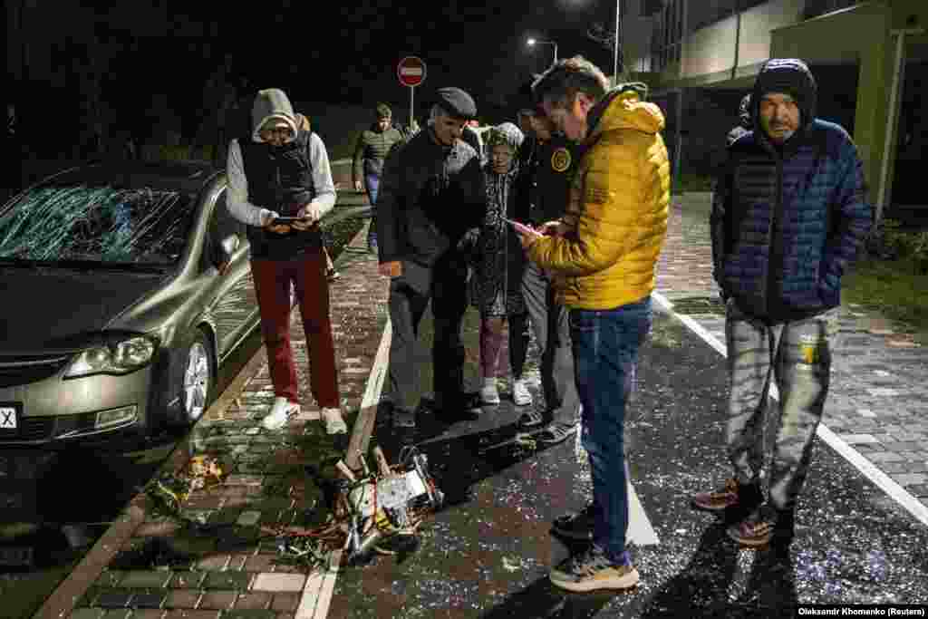 Stanovnici Kijeva posmatraju dio oborenog drona kamikaze za koji lokalne vlasti tvrde da je iranske proizvodnje Shahed-131/136.