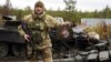 Військовослужбовець України показує емблему елітного підрозділу військ Росії біля знищених російських танків у селі Дмитрівка під Києвом, 2 квітня 2022 року, фото ілюстративне