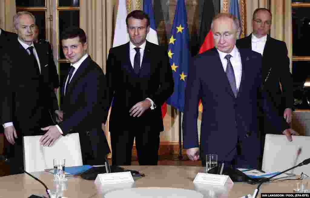 Президент України Володимир Зеленський (ліворуч), президент Франції Емманюель Макрон (позаду) та президент Росії Володимир Путін розсідаються на робочій зустрічі під час саміту у «нормандському форматі». На зустрічі було погоджене повне припинення вогню на сході України, яке має розпочатися до кінця 2019 року. Париж, Франція, 9 грудня 2019 року