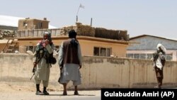 Taliban fighters stand guard in the city of Ghazni on August 13.