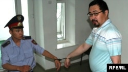 A police officer leads opposition activist Yermek Narymbaev to his sentencing in Almaty on June 22.