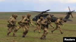 Soldați britanici coboară dintr-un elicopter militar american în timpul exercițiilor militare NATO Wind Spring 15, desfășurate în România (imagine de arhivă).