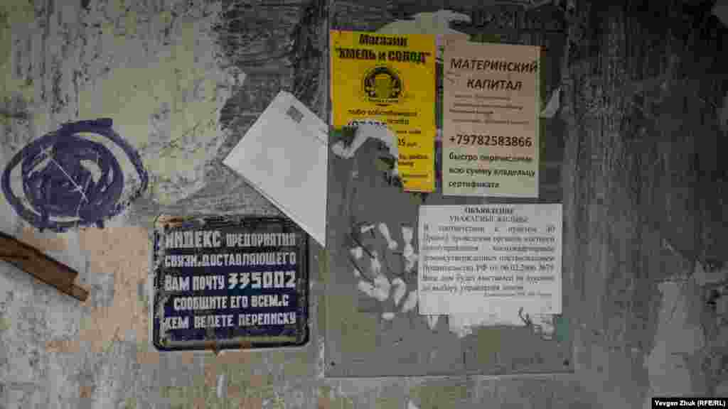 На вході до під'їзду табличка з радянським поштовим індексом, вцілілі позаторішні оголошення і квитанції за комуналку