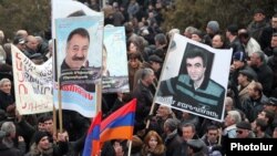 Armenia -- Demonstrators hold up pictures of jailed opposition members Aram Bareghamian (R) and Sasun Mikaelian, 1Mar2011.