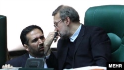 شمس‌الدین حسینی (چپ) دو زانو در کنار علی لاریجانی،‌ رئیس مجلس
