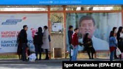 People wait for a bus in front of election campaign posters at a bus stop in the Kyrgyz capital, Bishkek. The country goes to the polls to elect a new president on October 15. 